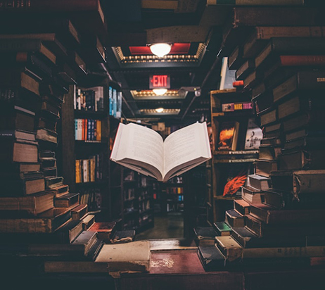 Livre flottant au milieu de srayons d'une bibliothèque