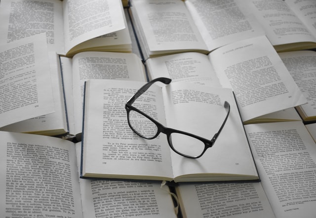 Paire de lunettes posée sur des livres ouverts, photo deTamara Gak via Unsplash